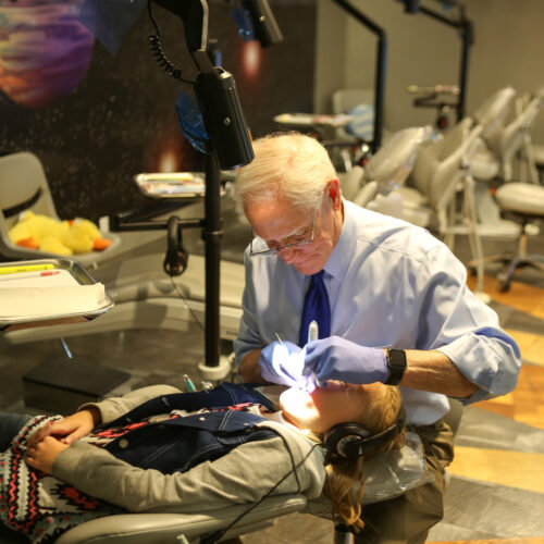 A person in a dental chair and being checked by a dentist