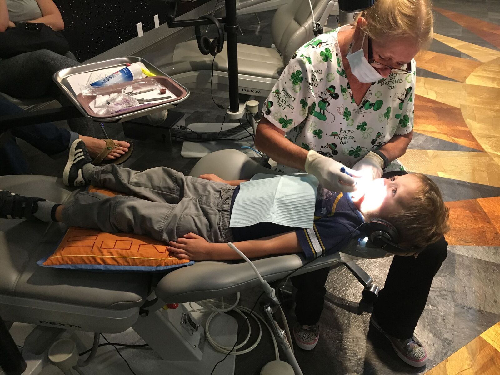 A child in a dental chair and being checked by a dentist